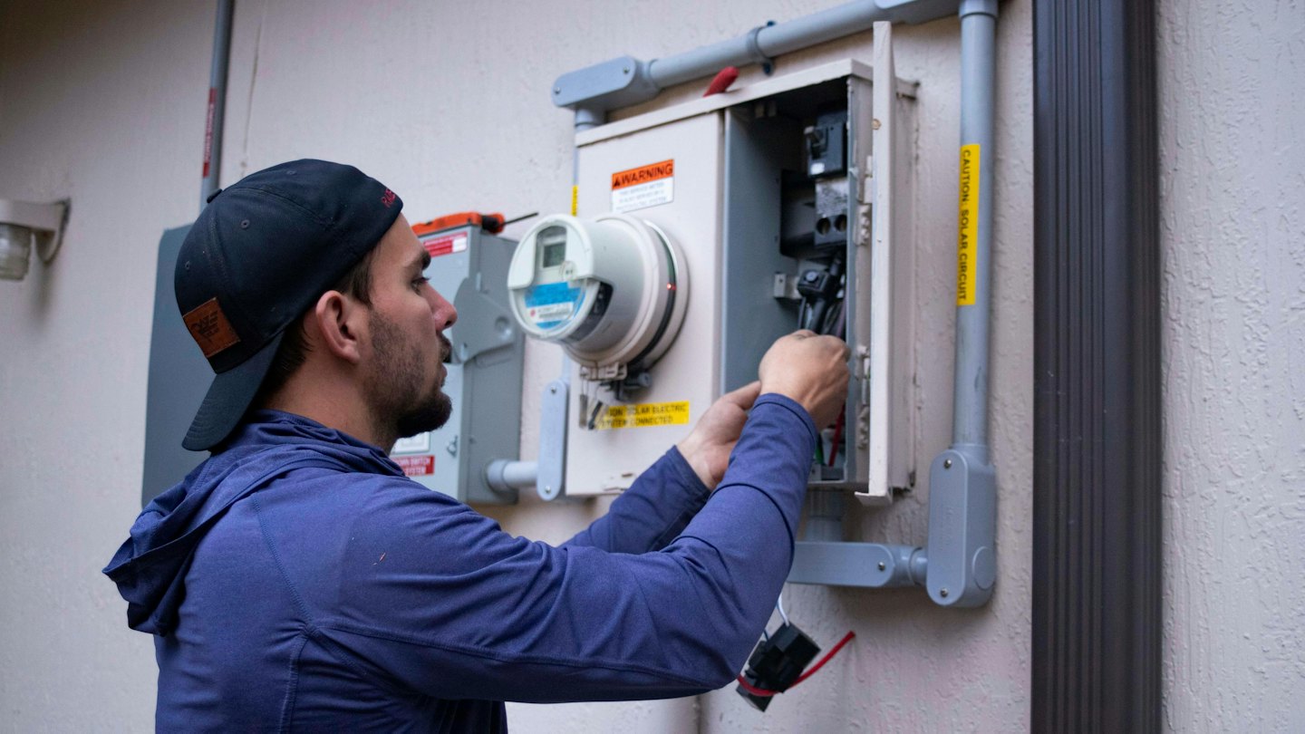 Tecnico che collega cavi in un quadro elettrico esterno.