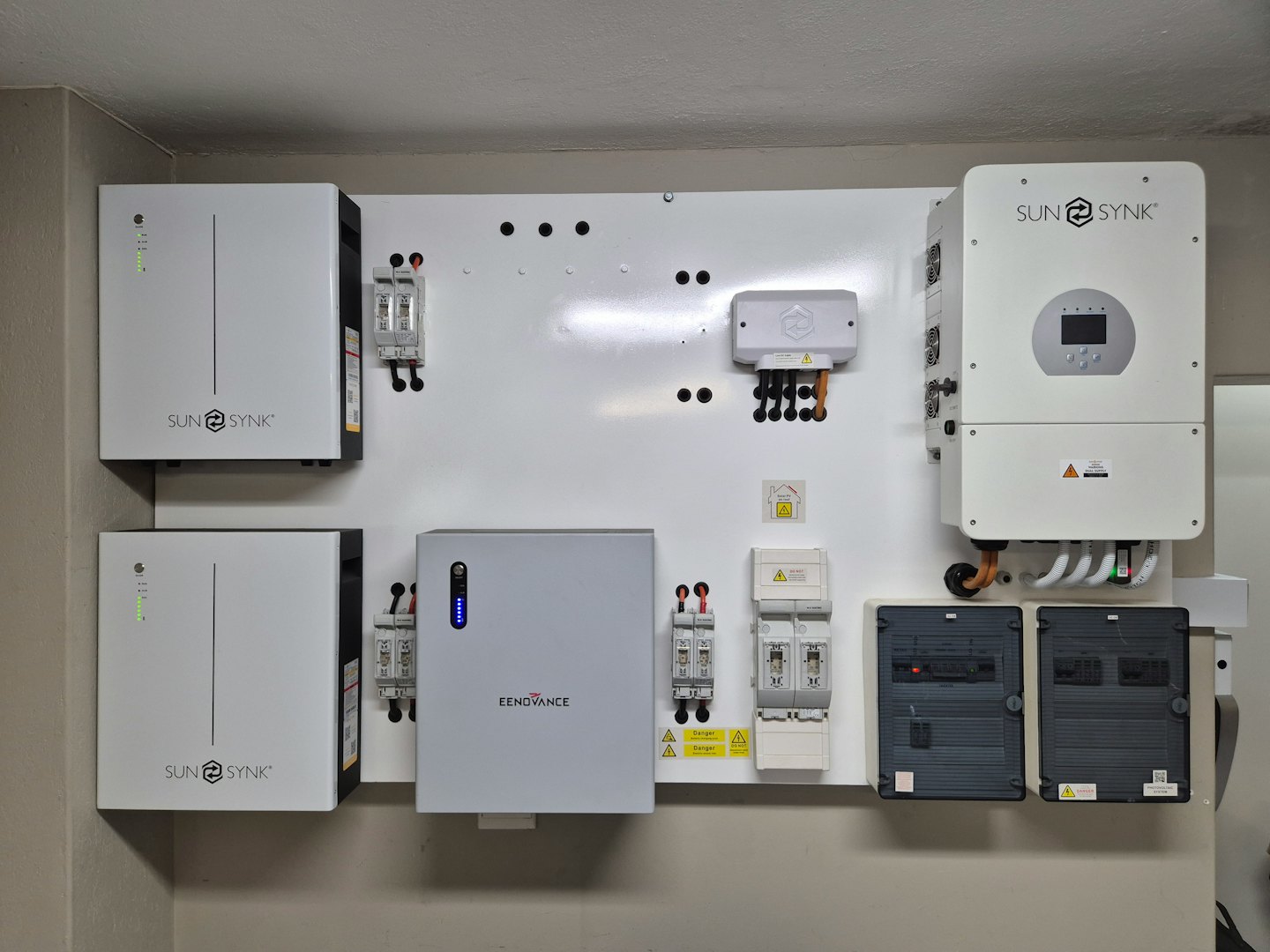Impianto energetico domestico con batterie e inverter su una parete bianca.